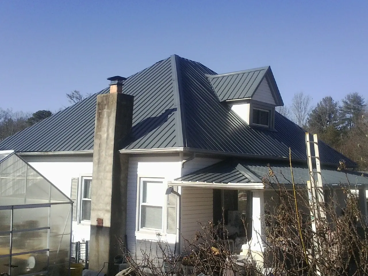 Dark blue standing seam metal roof on a white farmhouse with dormer — Slate & Tile Roof Repair by Roofing Brothers in Kennedyville