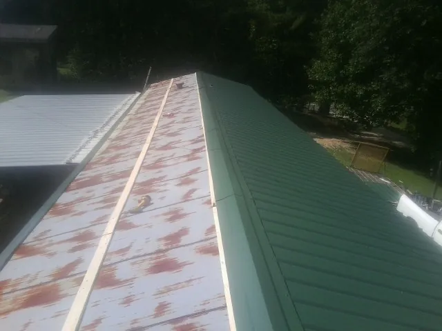 Old rusted panels beside newly installed green metal roofing — Wind Damage Roof Repair by Roofing Brothers in Kennedyville