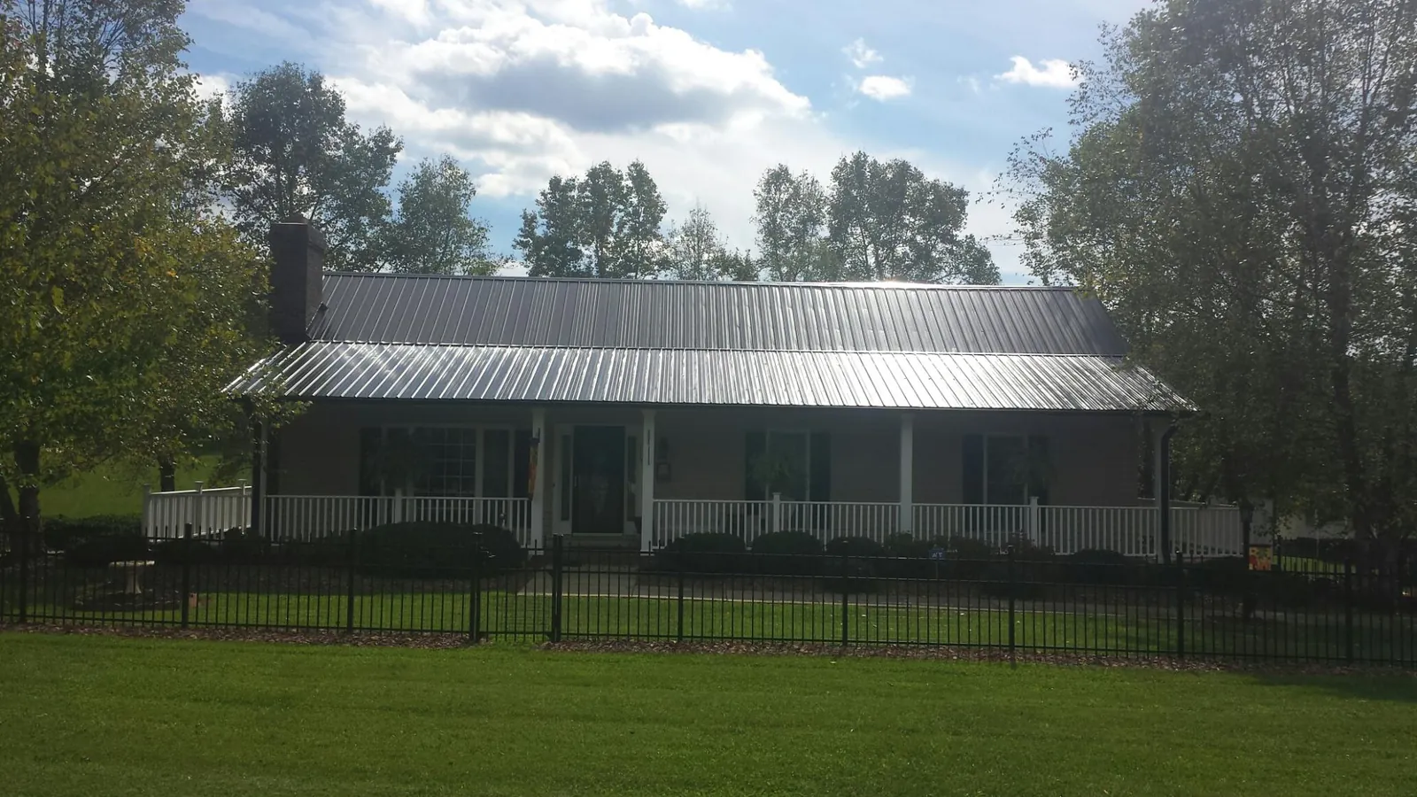 Gray metal roof on a brick ranch with a full width front porch — Gutter Guard Installation work by our crew in Kennedyville