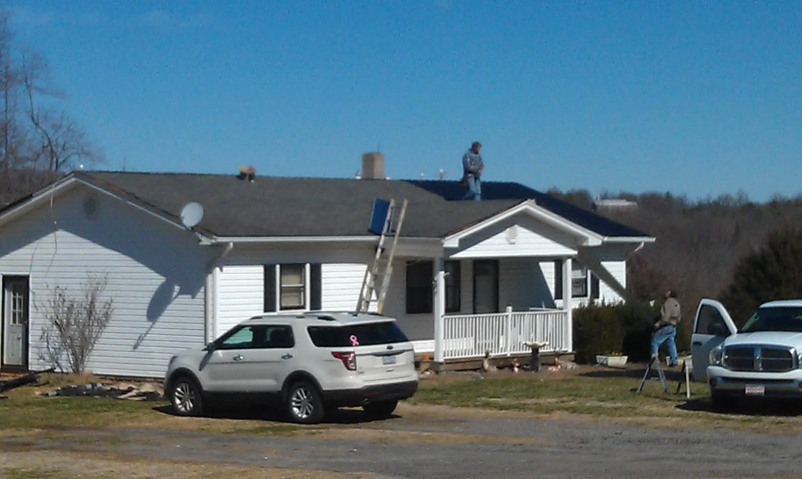 Roofers stripping shingles from a white ranch house roof in Kennedyville