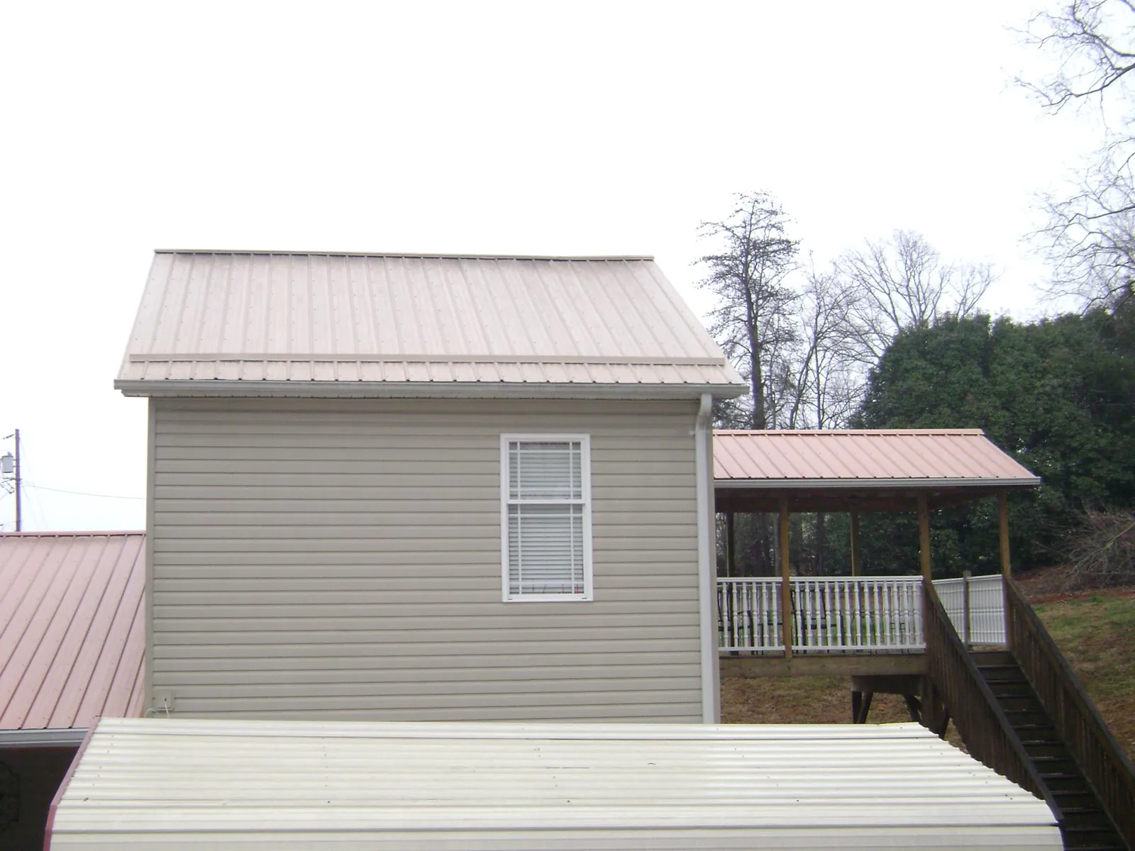 Tan metal roofs on a two story addition and attached porch, from a Roof Replacement job in Kennedyville