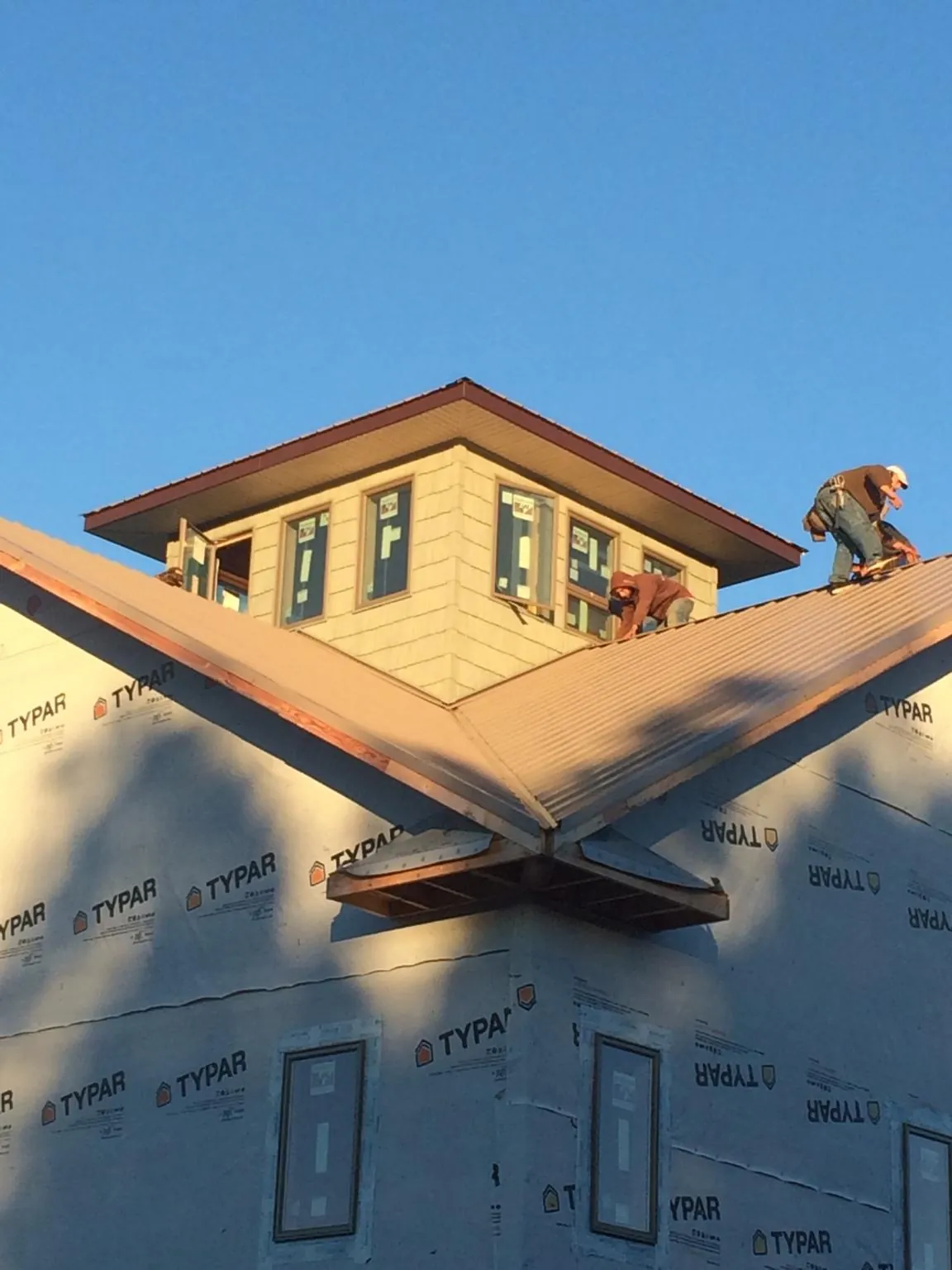 Roofers working around a rooftop cupola on a new metal roof at sunset — Roof Waterproofing in Kennedyville by Roofing Brothers